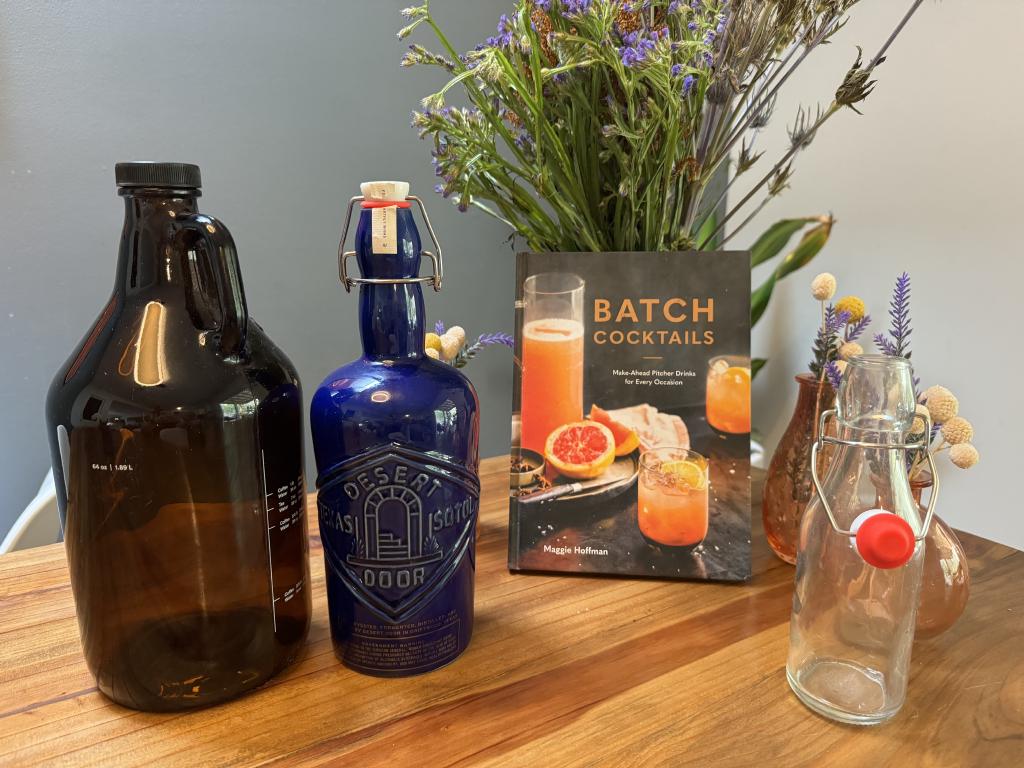 The Batch Cocktails book, surrounded by swingline bottles, a beer growler, and flowers